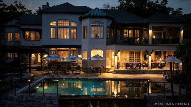 back of house featuring a patio, a balcony, and a fenced in pool