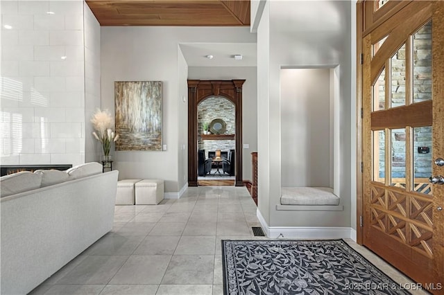 tiled foyer featuring a fireplace and baseboards