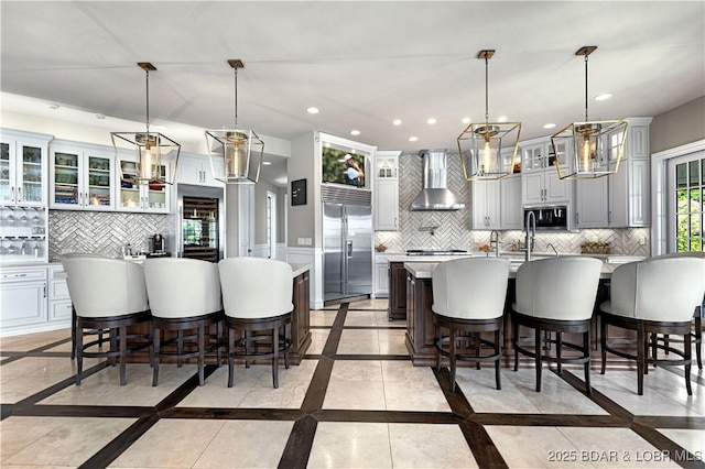 kitchen featuring a spacious island, decorative backsplash, appliances with stainless steel finishes, and wall chimney exhaust hood