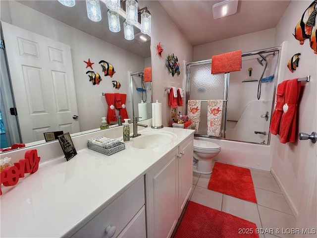 bathroom featuring vanity, baseboards, tile patterned floors, toilet, and combined bath / shower with glass door