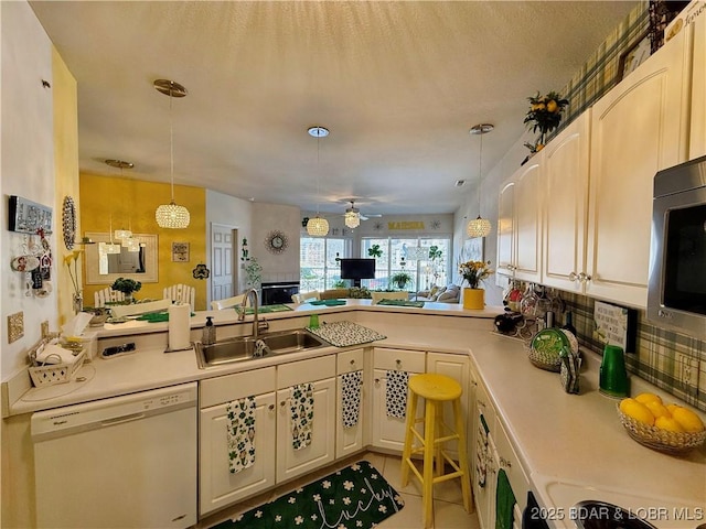 kitchen with dishwasher, light countertops, hanging light fixtures, and a sink