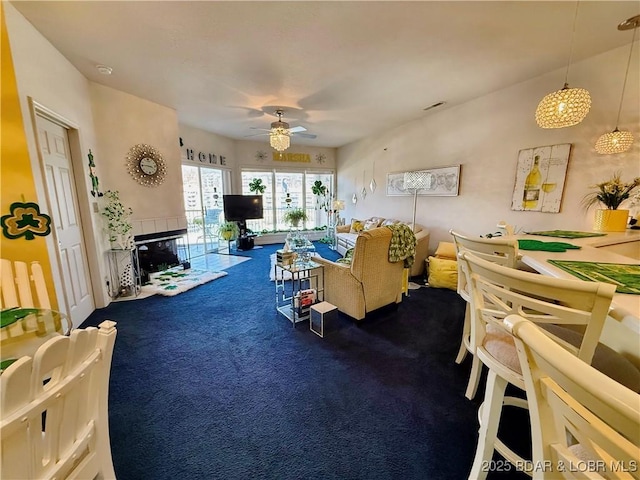 living room featuring visible vents, ceiling fan, carpet flooring, and a tiled fireplace