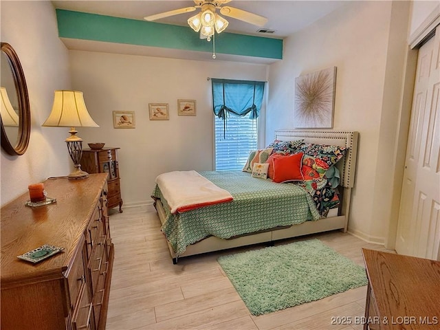 bedroom with a ceiling fan, light wood-style floors, visible vents, and baseboards