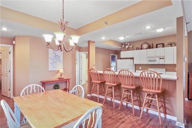 dining room featuring light wood finished floors, recessed lighting, baseboards, and an inviting chandelier