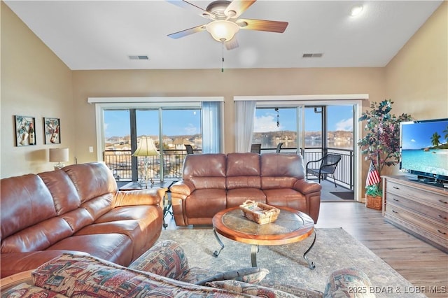 living area with visible vents, lofted ceiling, wood finished floors, and a ceiling fan