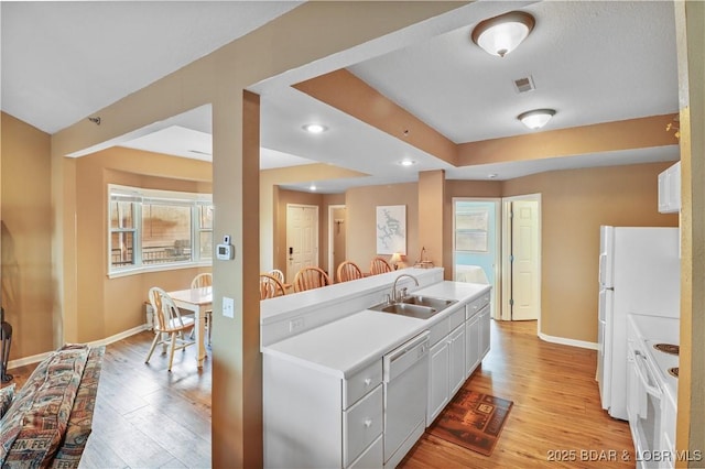 kitchen featuring a sink, visible vents, white appliances, and light wood finished floors