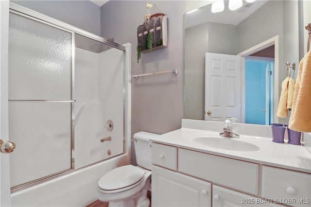 bathroom with toilet, vanity, and bath / shower combo with glass door