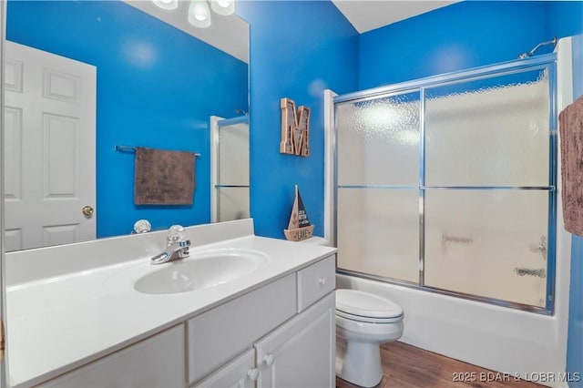 bathroom featuring enclosed tub / shower combo, toilet, wood finished floors, and vanity