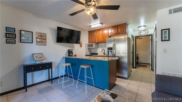 kitchen featuring white microwave, visible vents, a peninsula, stainless steel fridge with ice dispenser, and brown cabinets