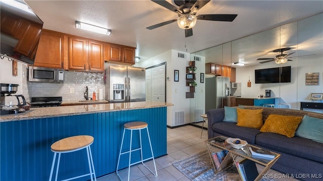 kitchen with open floor plan, appliances with stainless steel finishes, a kitchen breakfast bar, a peninsula, and a sink