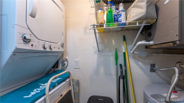 laundry area with stacked washer and dryer and a textured wall