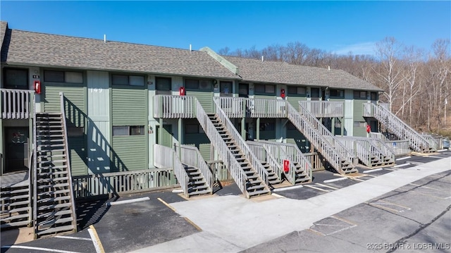 view of building exterior with stairs and uncovered parking