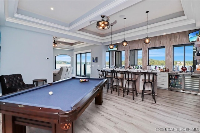 game room with a tray ceiling, crown molding, and light wood finished floors