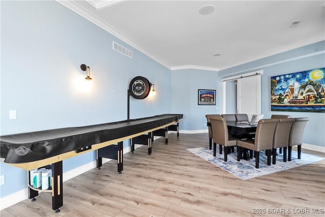 dining room featuring visible vents, ornamental molding, wood finished floors, a barn door, and baseboards