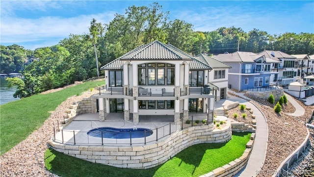 back of property with stucco siding, a tile roof, a patio, an outdoor pool, and a balcony