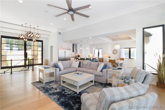 living room with recessed lighting, visible vents, light wood-style floors, and ceiling fan with notable chandelier