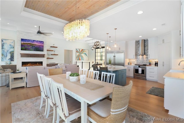 dining space featuring recessed lighting, light wood-style flooring, wood ceiling, and a large fireplace