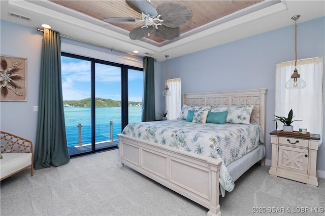 bedroom with access to exterior, visible vents, a water view, light colored carpet, and a raised ceiling