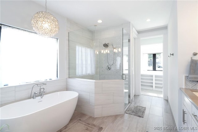 full bathroom with a soaking tub, a stall shower, and vanity