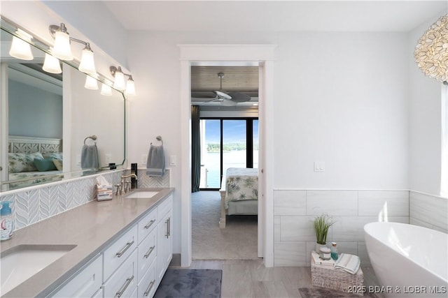 ensuite bathroom featuring a sink, double vanity, a freestanding bath, and connected bathroom