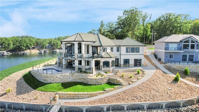 rear view of house with a patio, a balcony, stairs, a water view, and a tiled roof