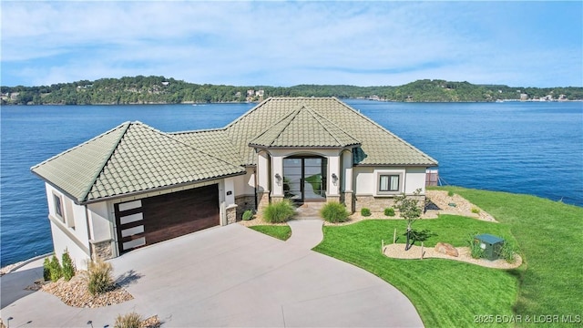 view of front facade with a tiled roof, stucco siding, driveway, and a front yard