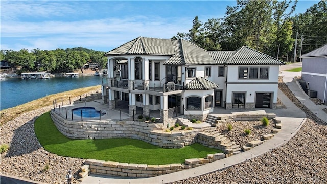 back of property featuring a tiled roof, stucco siding, a balcony, a patio area, and stone siding