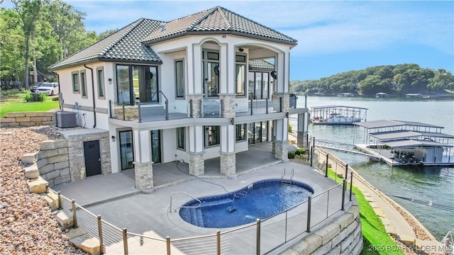 back of house featuring stucco siding, a water view, a tile roof, central AC, and a patio area