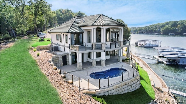 back of house with a patio, a balcony, a yard, a tile roof, and central air condition unit