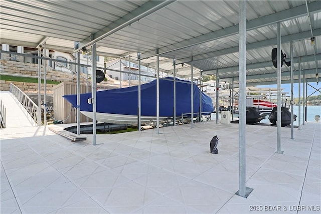 view of car parking featuring a dock, a water view, and boat lift