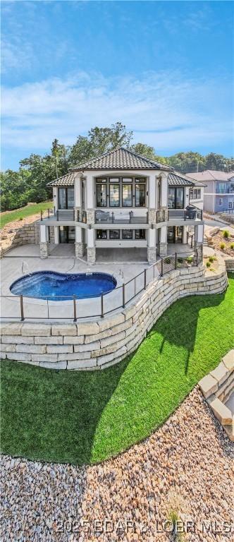 back of house featuring an outdoor pool, a patio, and a tile roof