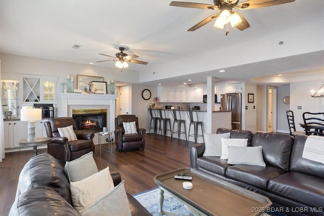 living room with dark wood finished floors, a glass covered fireplace, recessed lighting, and a ceiling fan