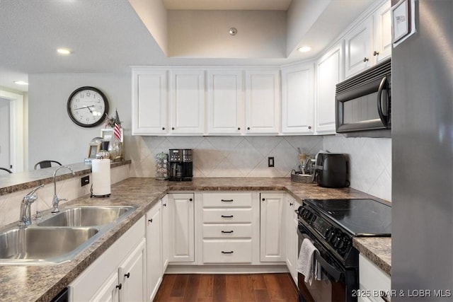 kitchen featuring dark wood-style floors, a sink, black appliances, white cabinets, and backsplash