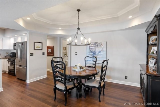 dining area with dark wood-style floors, a chandelier, baseboards, and a tray ceiling