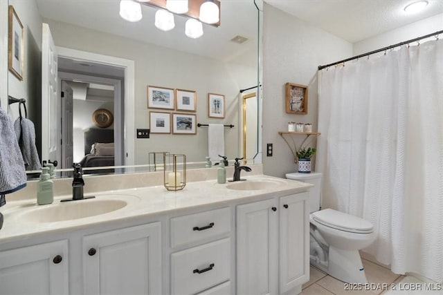 bathroom with a sink, toilet, double vanity, and tile patterned floors