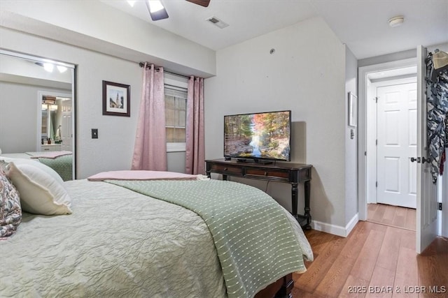 bedroom with ceiling fan, visible vents, baseboards, and wood finished floors