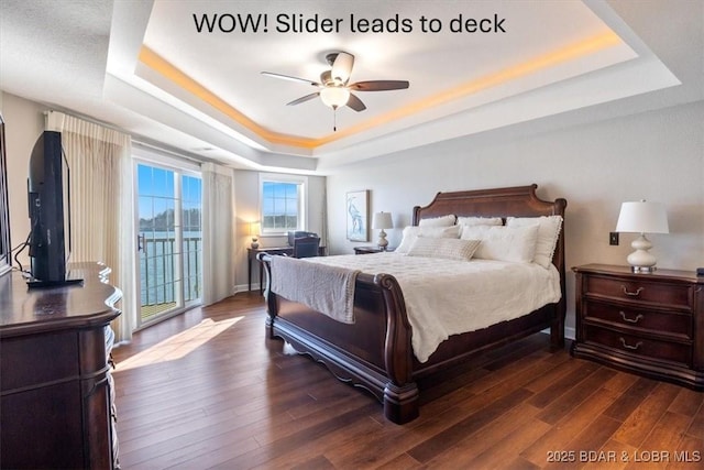 bedroom featuring dark wood-style floors, a raised ceiling, a ceiling fan, and access to exterior