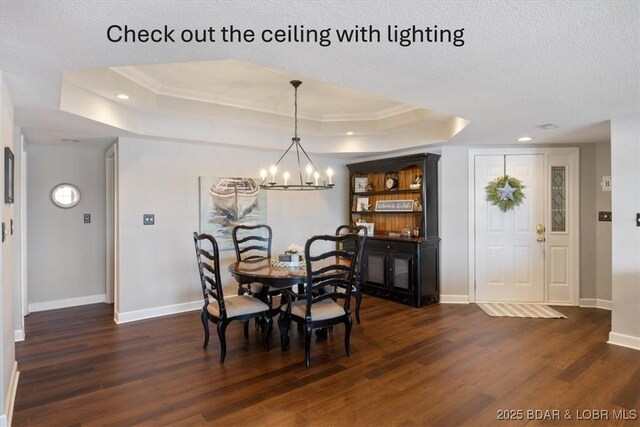 dining area with dark wood finished floors, a tray ceiling, and baseboards