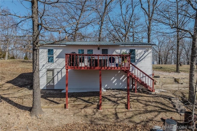 back of house featuring stairway, metal roof, and a deck