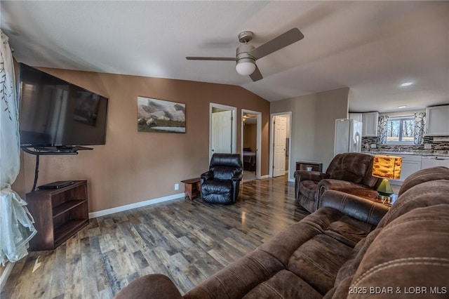 living room with a ceiling fan, vaulted ceiling, wood finished floors, and baseboards