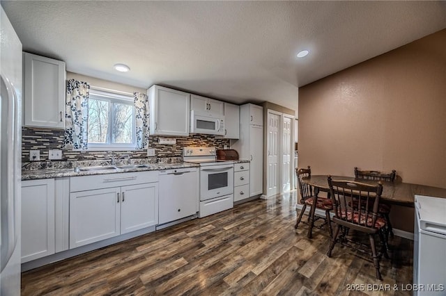 kitchen featuring white appliances, dark wood-style floors, a sink, white cabinetry, and tasteful backsplash