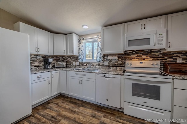 kitchen with dark wood finished floors, white appliances, decorative backsplash, and a sink