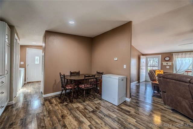 dining room featuring dark wood finished floors, lofted ceiling, and baseboards