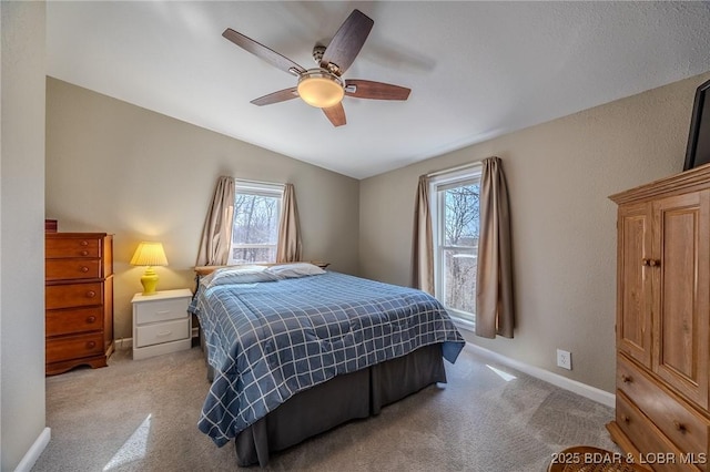 bedroom with multiple windows, light carpet, baseboards, and ceiling fan