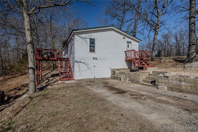 view of side of property with stairway and driveway