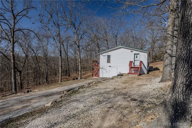 exterior space featuring a view of trees and dirt driveway