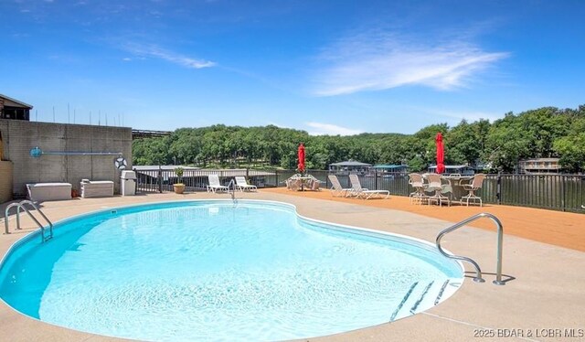 community pool with a patio area and fence