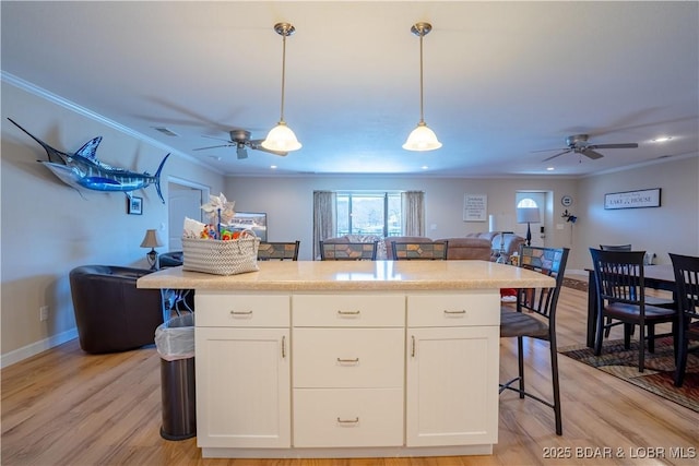 kitchen with crown molding, open floor plan, pendant lighting, light wood-style flooring, and white cabinetry