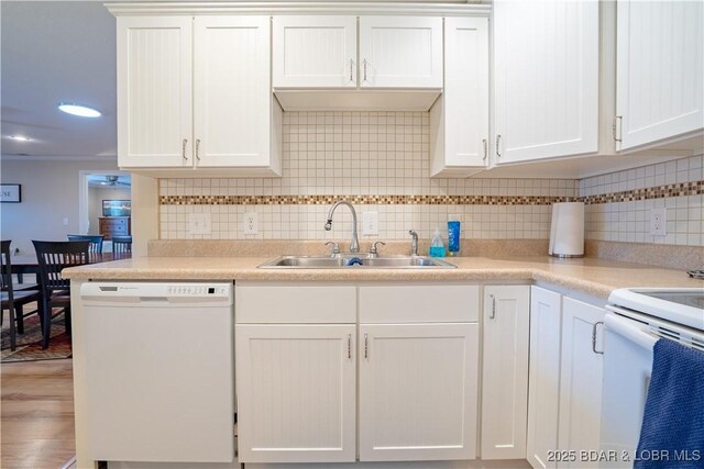 kitchen with a sink, white appliances, tasteful backsplash, and white cabinets