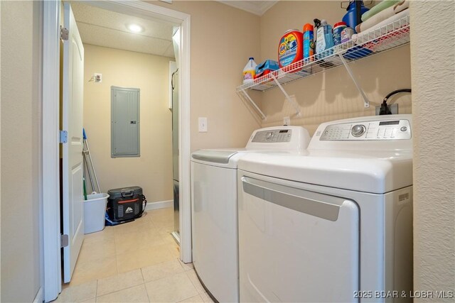 clothes washing area featuring electric panel, washing machine and dryer, baseboards, and light tile patterned flooring